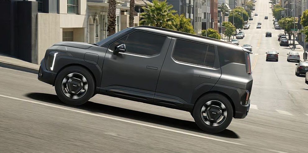 Kia Syros EV driving on a city street, side profile